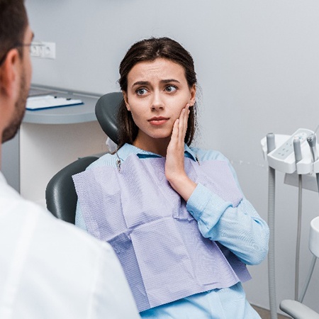 Closeup of concerned woman with toothache talking to dentist