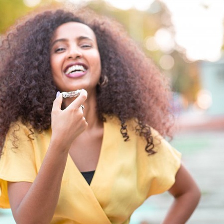 a woman smiling while holding Angel Aligners