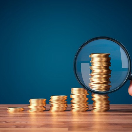 a stack of coins with a magnifying glass