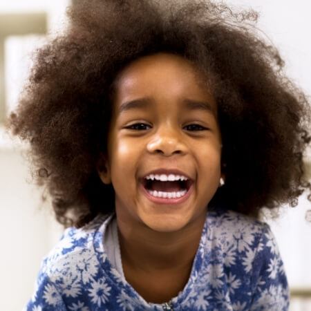 Child laughing after visiting children's dentist for dental checkups and teeth cleanings for kids