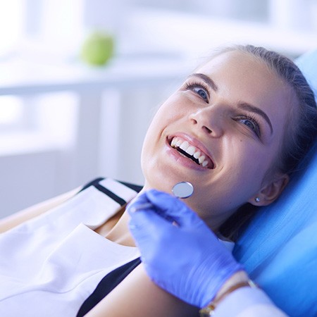 young woman smiling while sitting in treatment chair