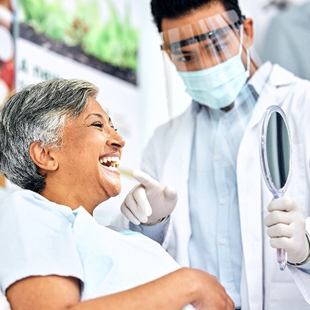Patient smiling at reflection in mirror with dentist