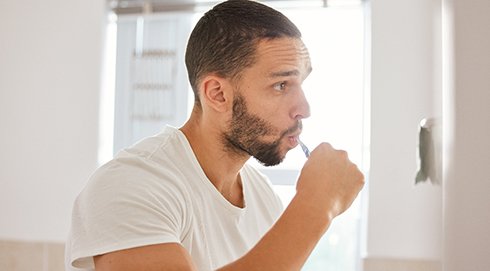 Man brushing his teeth in bathroom