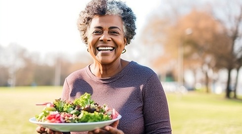 Smiling woman holding bowl of salad outside