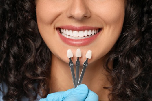 Man in navy scrubs holding clear aligner