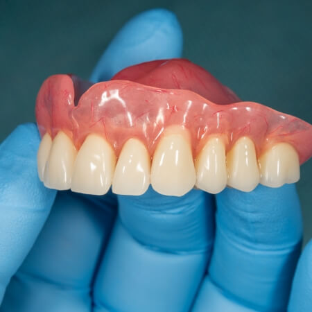 Hand holding a full set of dentures