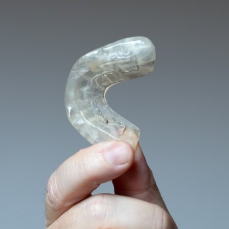 Hand holding clear nightguard for bruxism