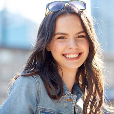 Woman with sunglasses on head outside and smiling