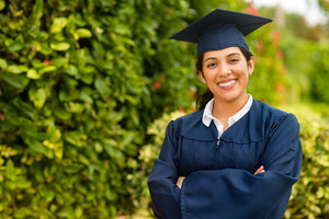 Woman in a graduation outfit smiling with arms folded