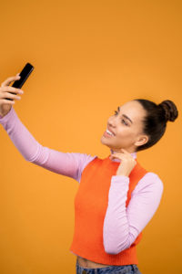 Smiling young woman taking a selfie with a cellphone